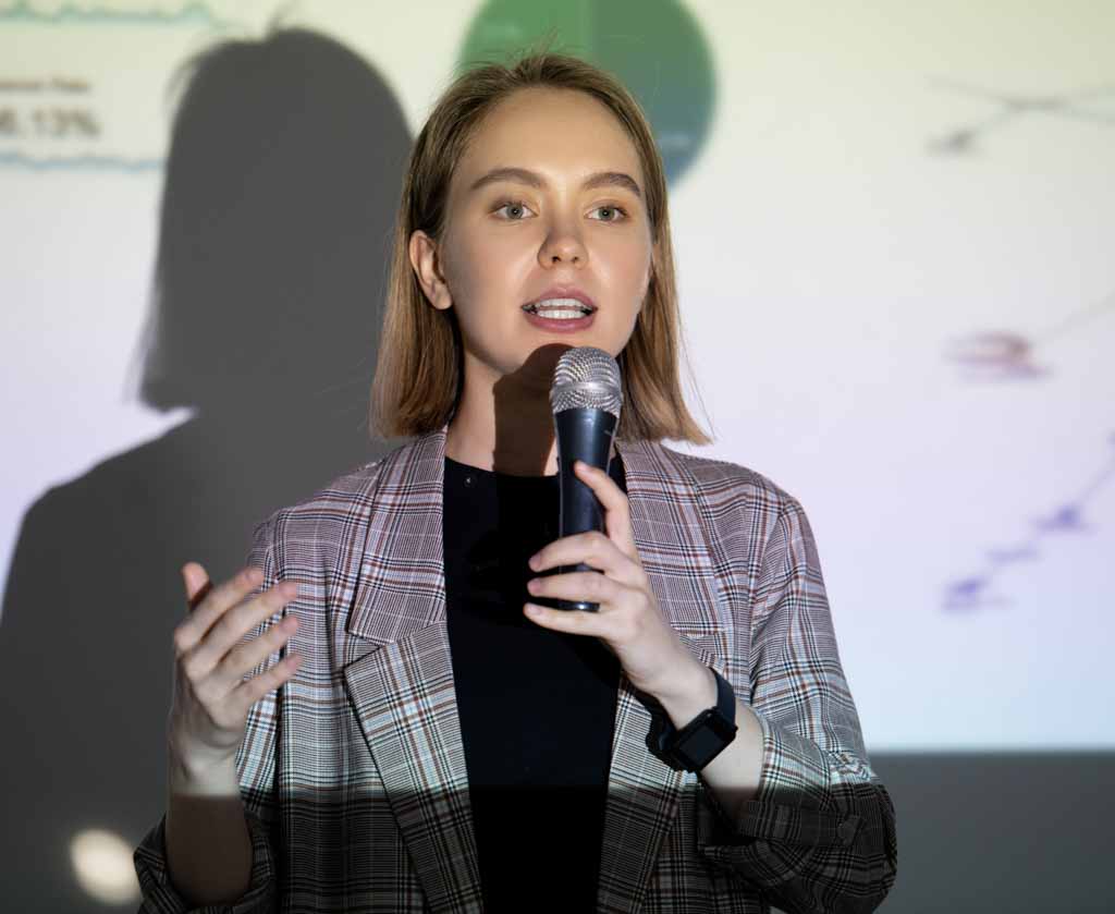 Selbstbewusste junge Wissenschaftlerin spricht auf einer Konferenz in ein Mikrofon über ihren Erfolg.